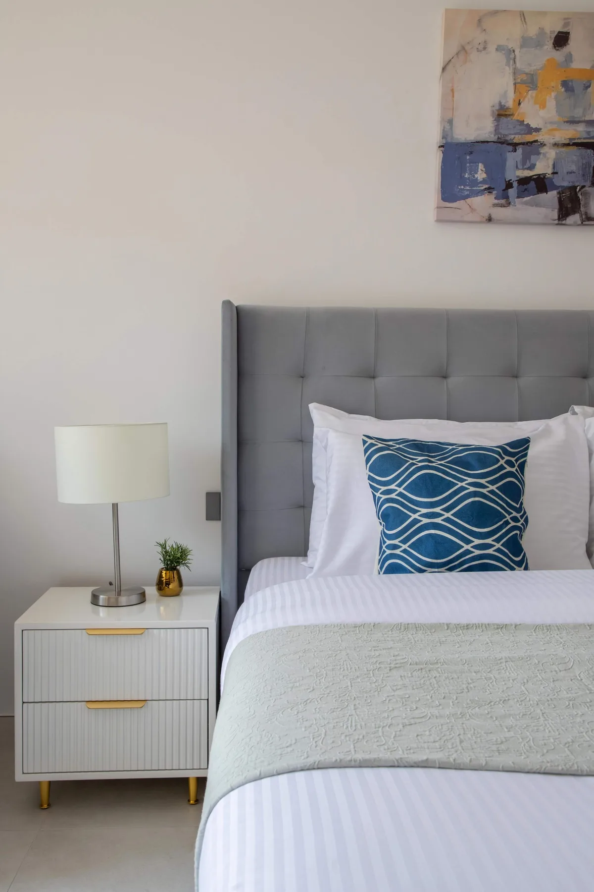 Un dormitorio con una cama tendida y un cojín decorativo azul estampado.