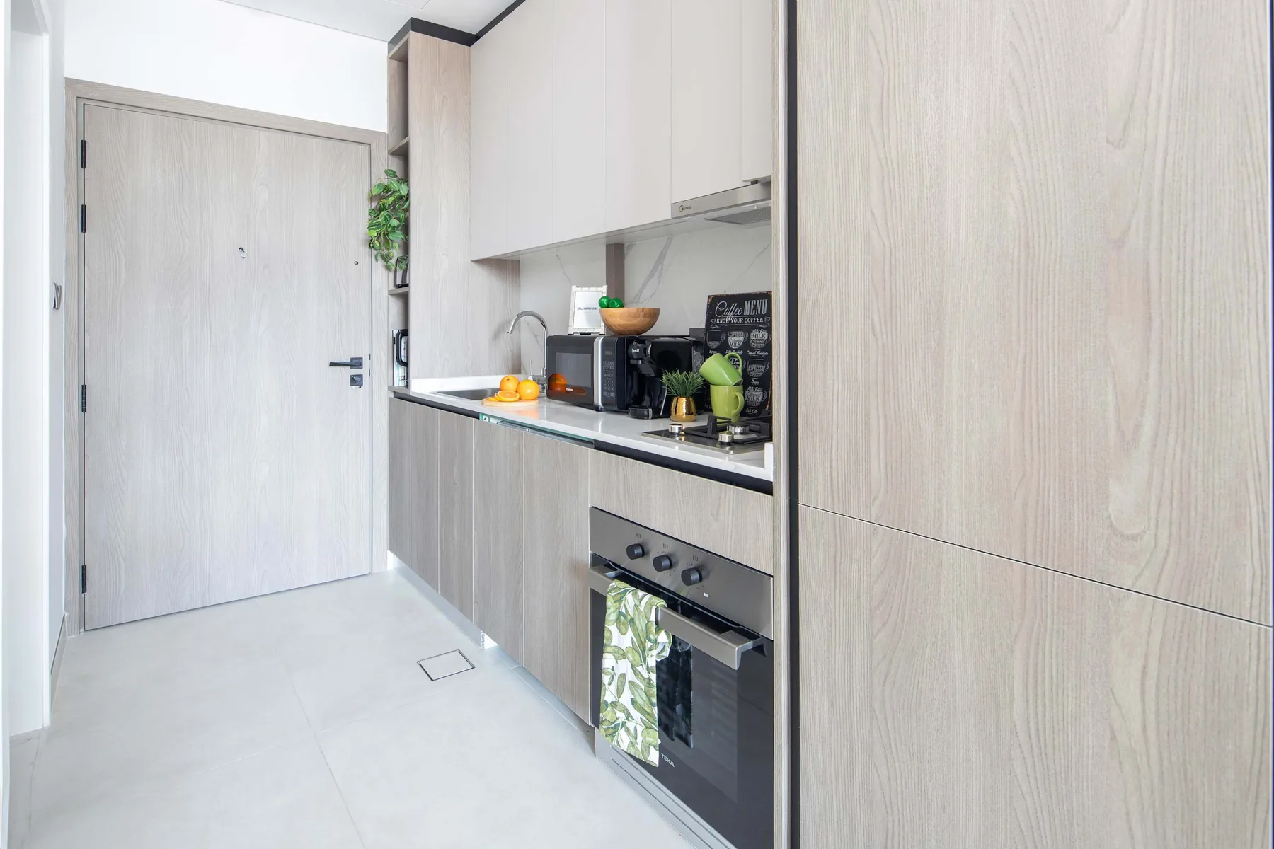 Una cocina compacta con gabinetes de madera clara, una encimera y electrodomésticos integrados.