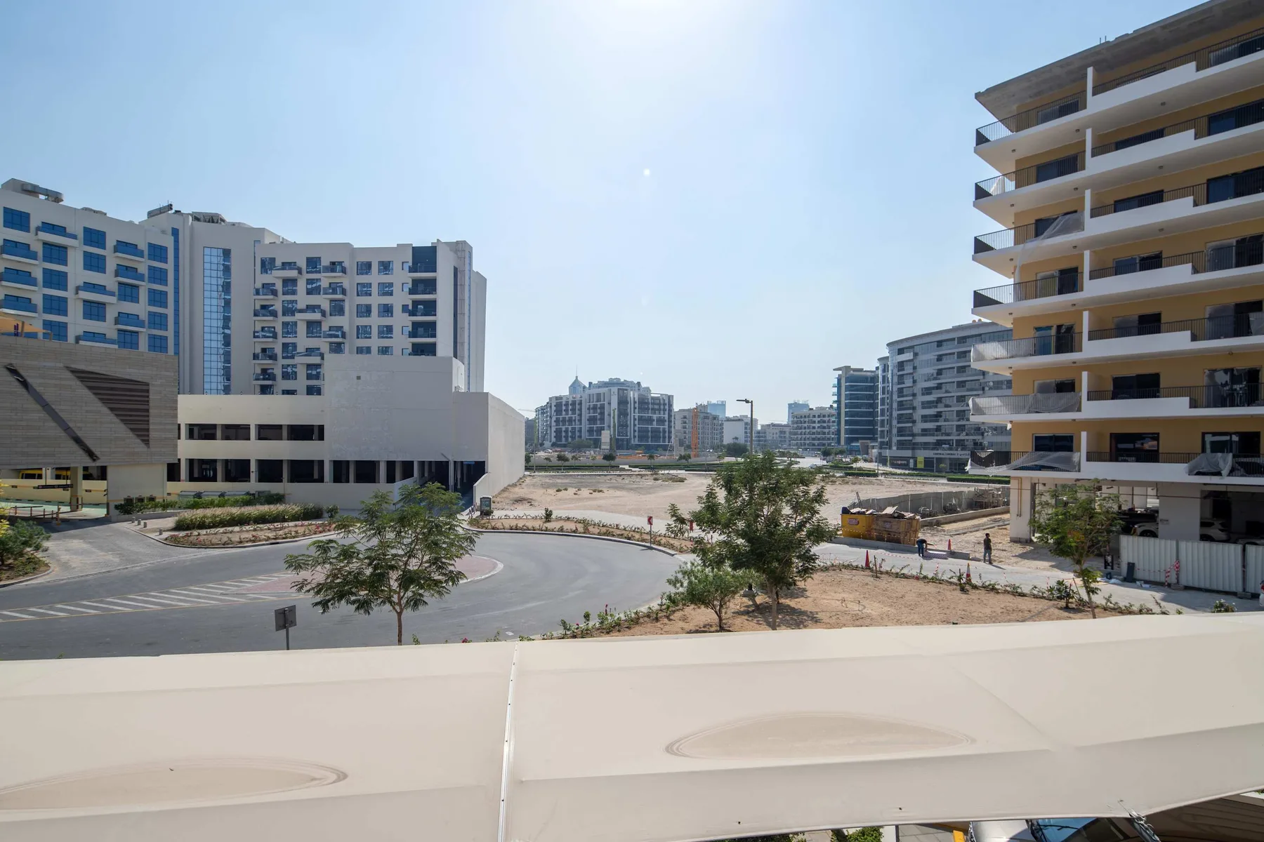 Vista urbana desde un balcón con edificios modernos y una rotonda.