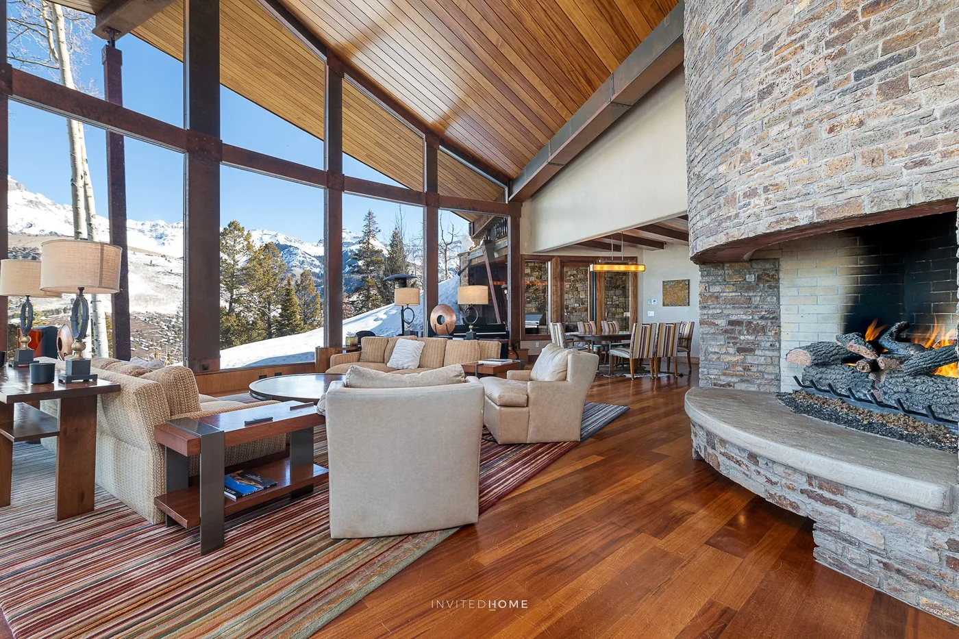 Una amplia sala de estar con grandes ventanas, asientos y una chimenea de piedra.
