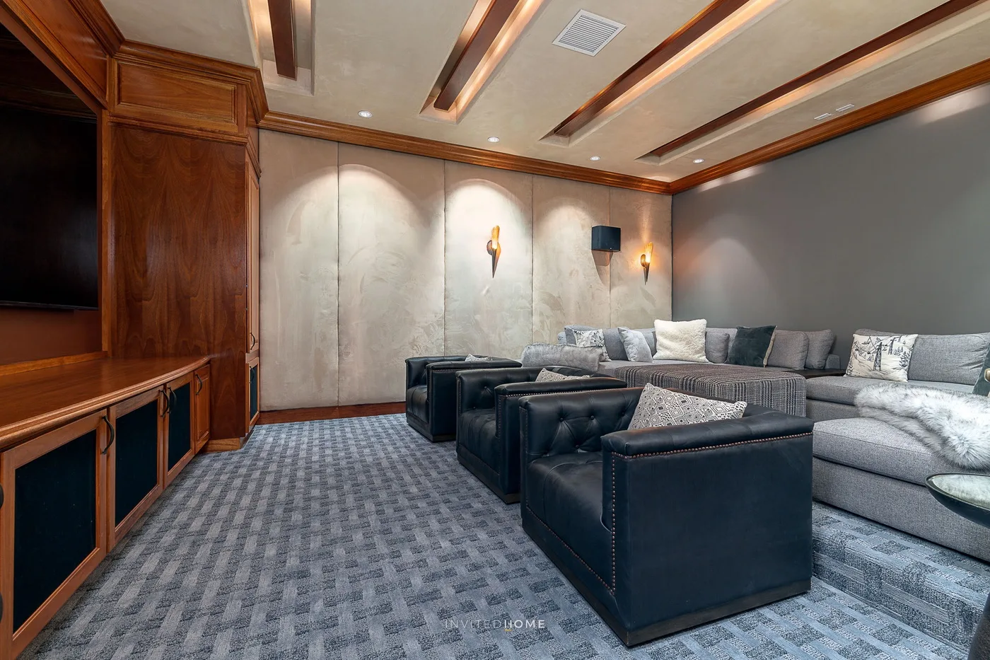Una sala de estar con asientos oscuros, un sofá seccional y muebles de madera.