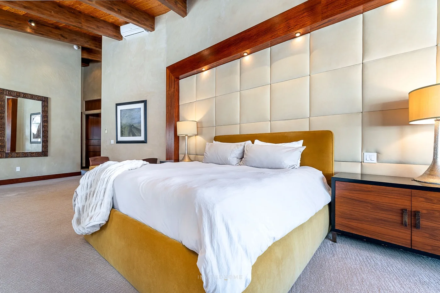 Un dormitorio con una cama bien arreglada y paneles acolchados en la pared.
