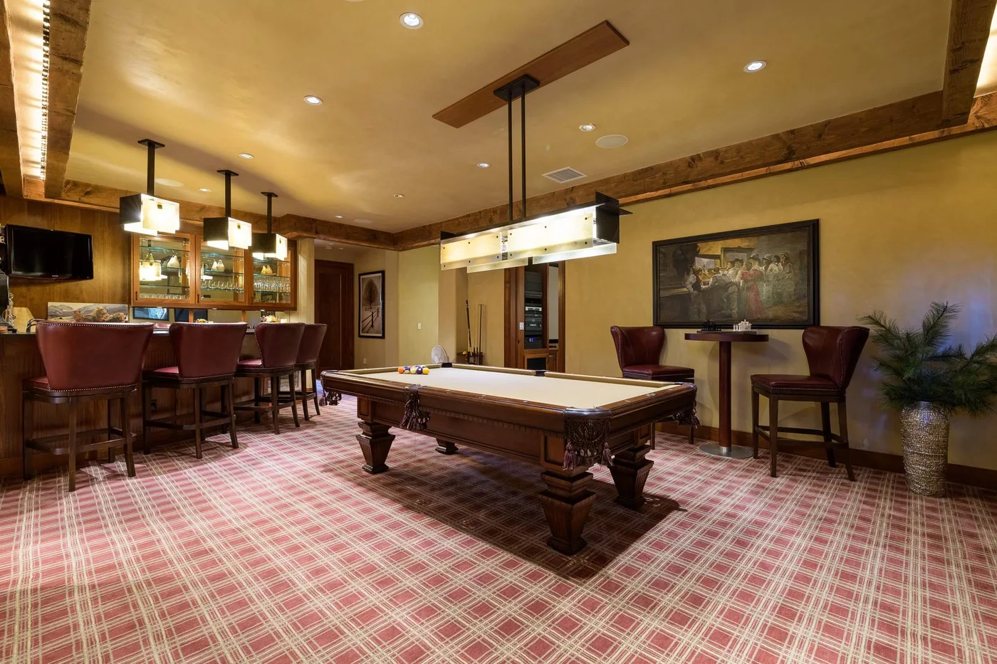 Una sala de juegos con una mesa de billar y asientos de bar.
