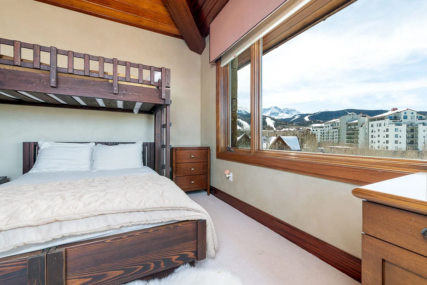 Un dormitorio con una litera y una gran ventana con vistas a montañas nevadas.
