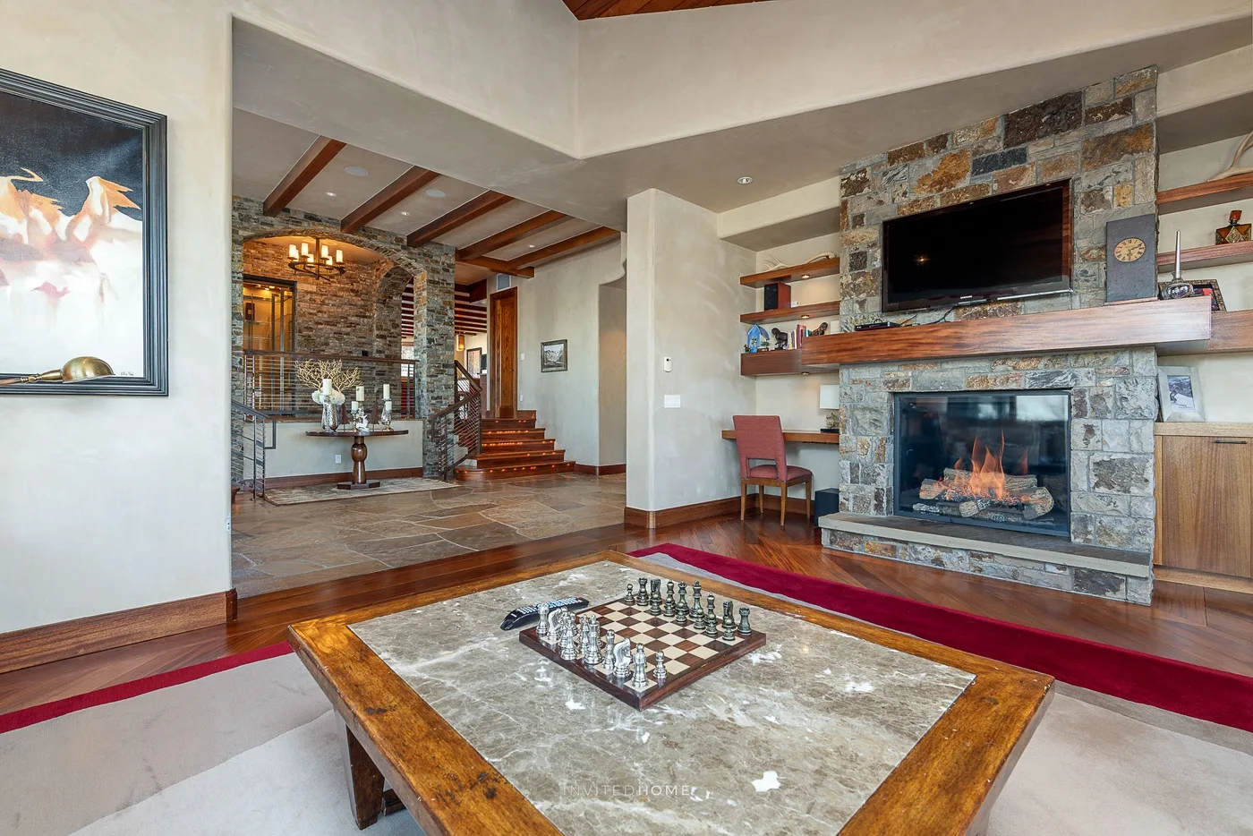 Una sala de estar con chimenea de piedra, televisor y un tablero de ajedrez sobre la mesa de centro.