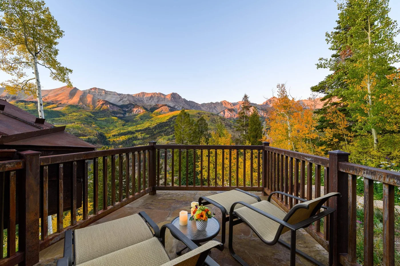 Una terraza de madera con asientos ofrece vistas a un paisaje montañoso.