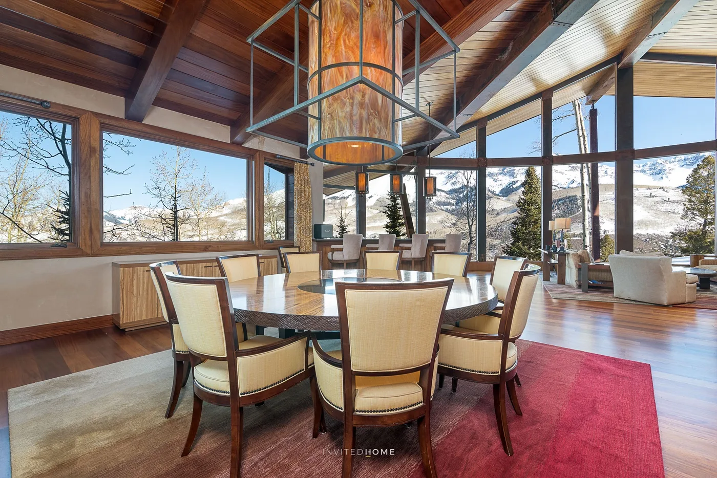 Comedor con una mesa grande y ventanas con vistas a un paisaje montañoso.