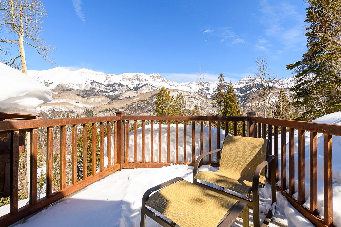 Una terraza cubierta de nieve con asientos ofrece vistas a un paisaje montañoso.