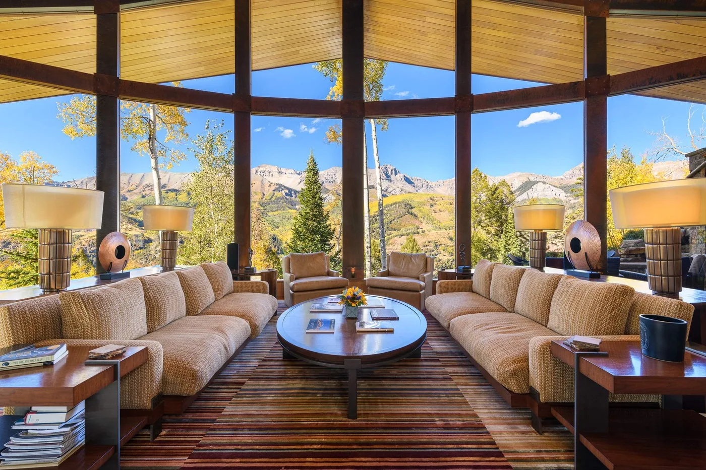 A spacious living room with curved seating and large windows overlooking a mountain landscape.