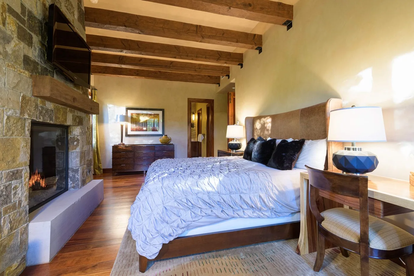 Un dormitorio con una cama, una chimenea de piedra y vigas de madera expuestas.