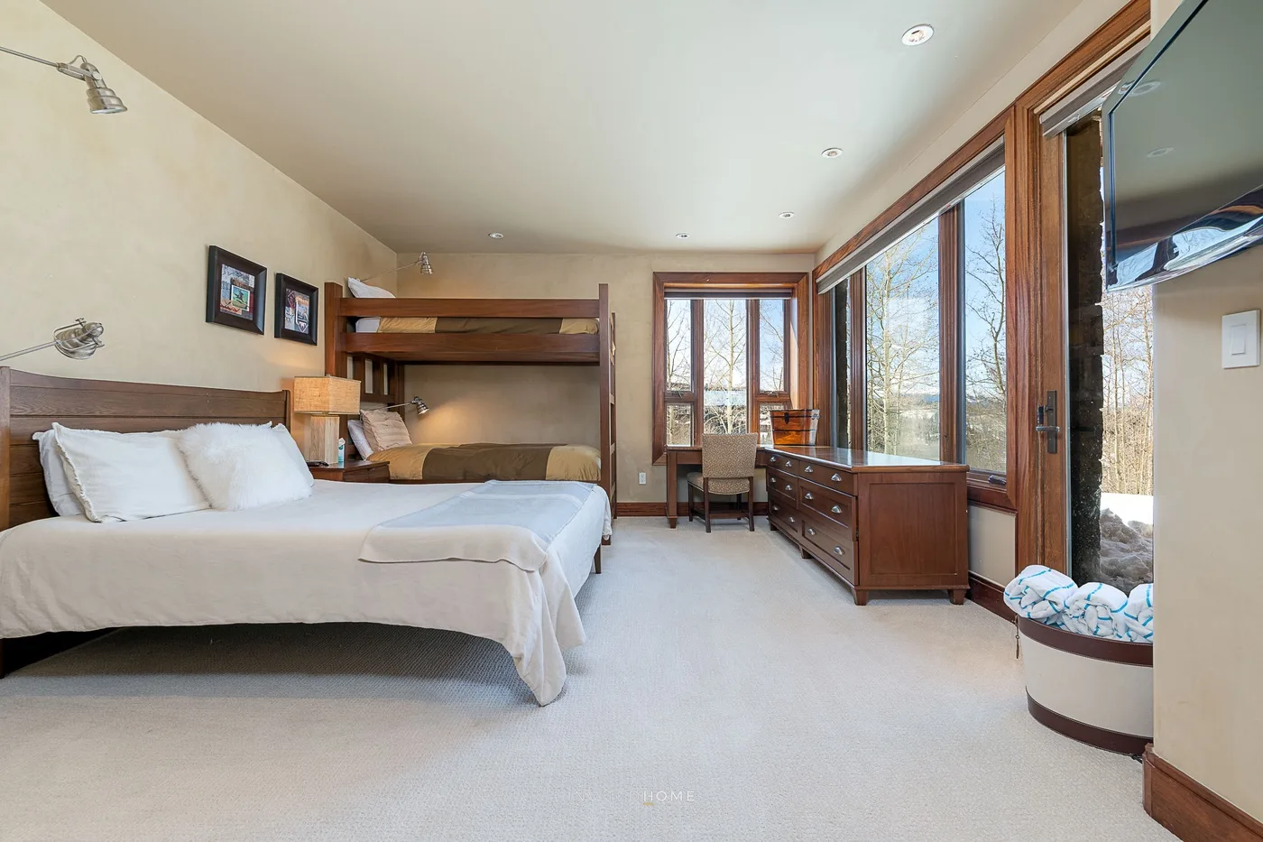 Un dormitorio luminoso con una cama, literas y grandes ventanas.