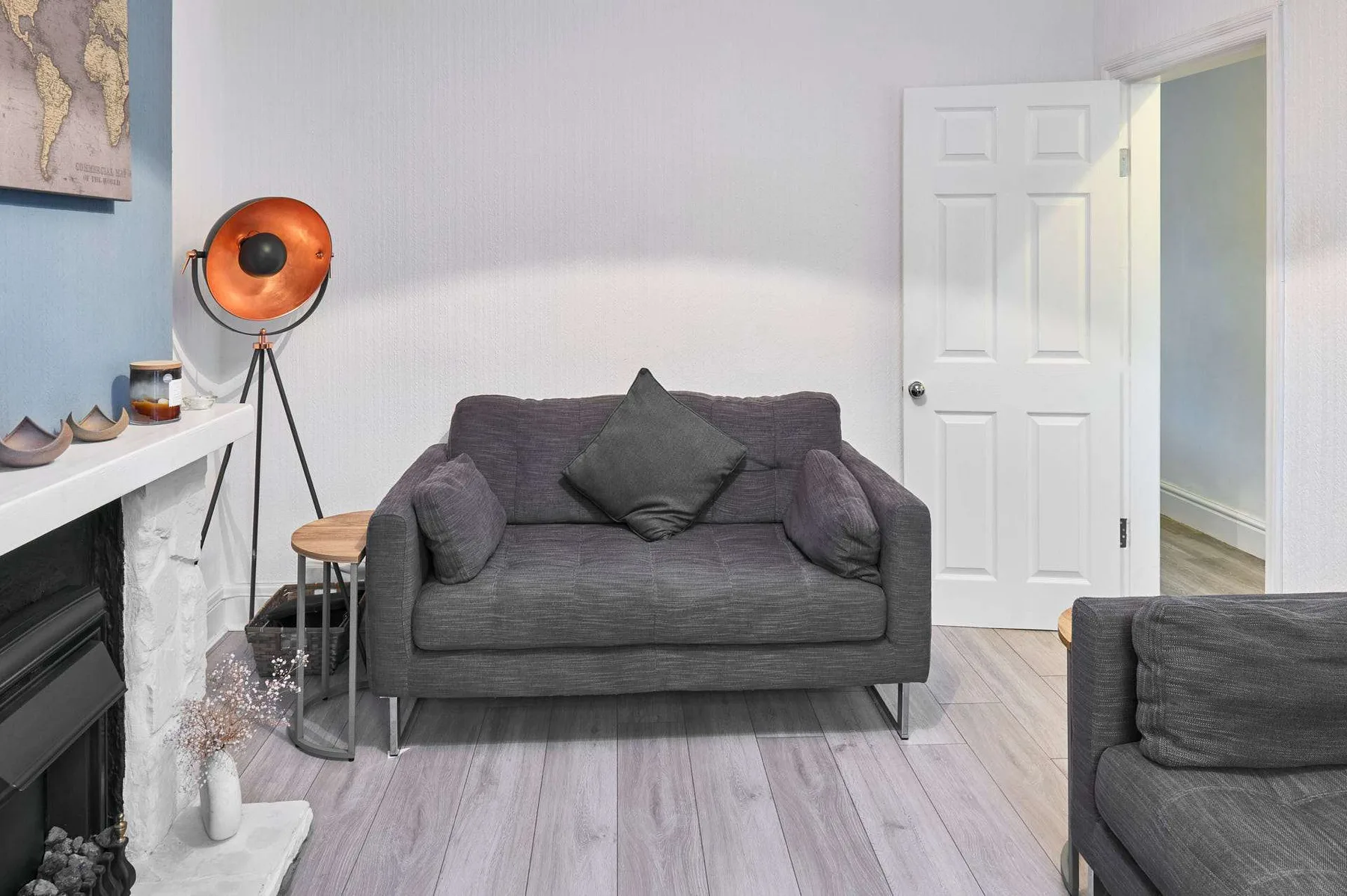 Una sala de estar con un sofá gris, una lámpara de pie y una chimenea.