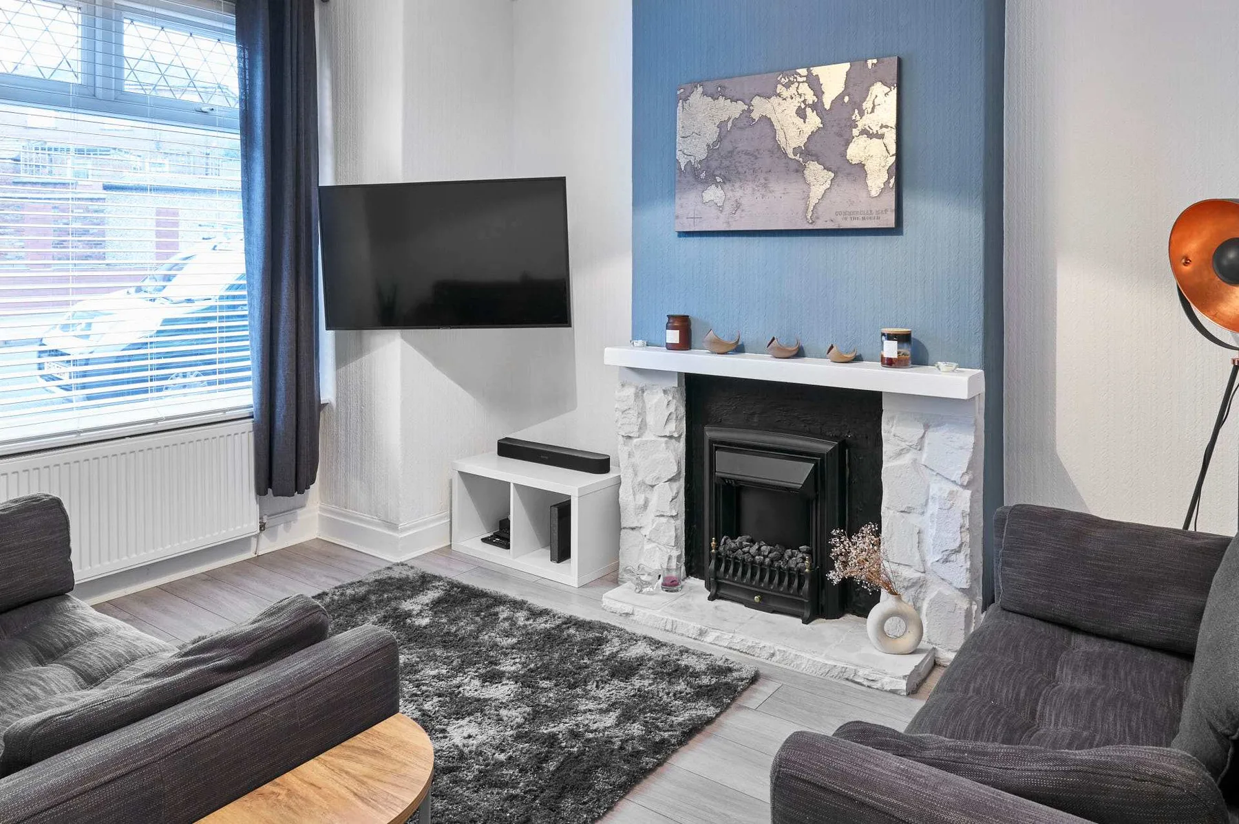 Una sala de estar con asientos oscuros, un televisor y una chimenea.