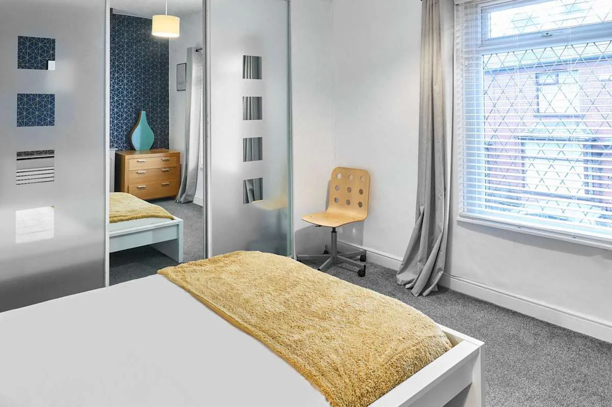Un dormitorio con una cama, una silla y una ventana grande.