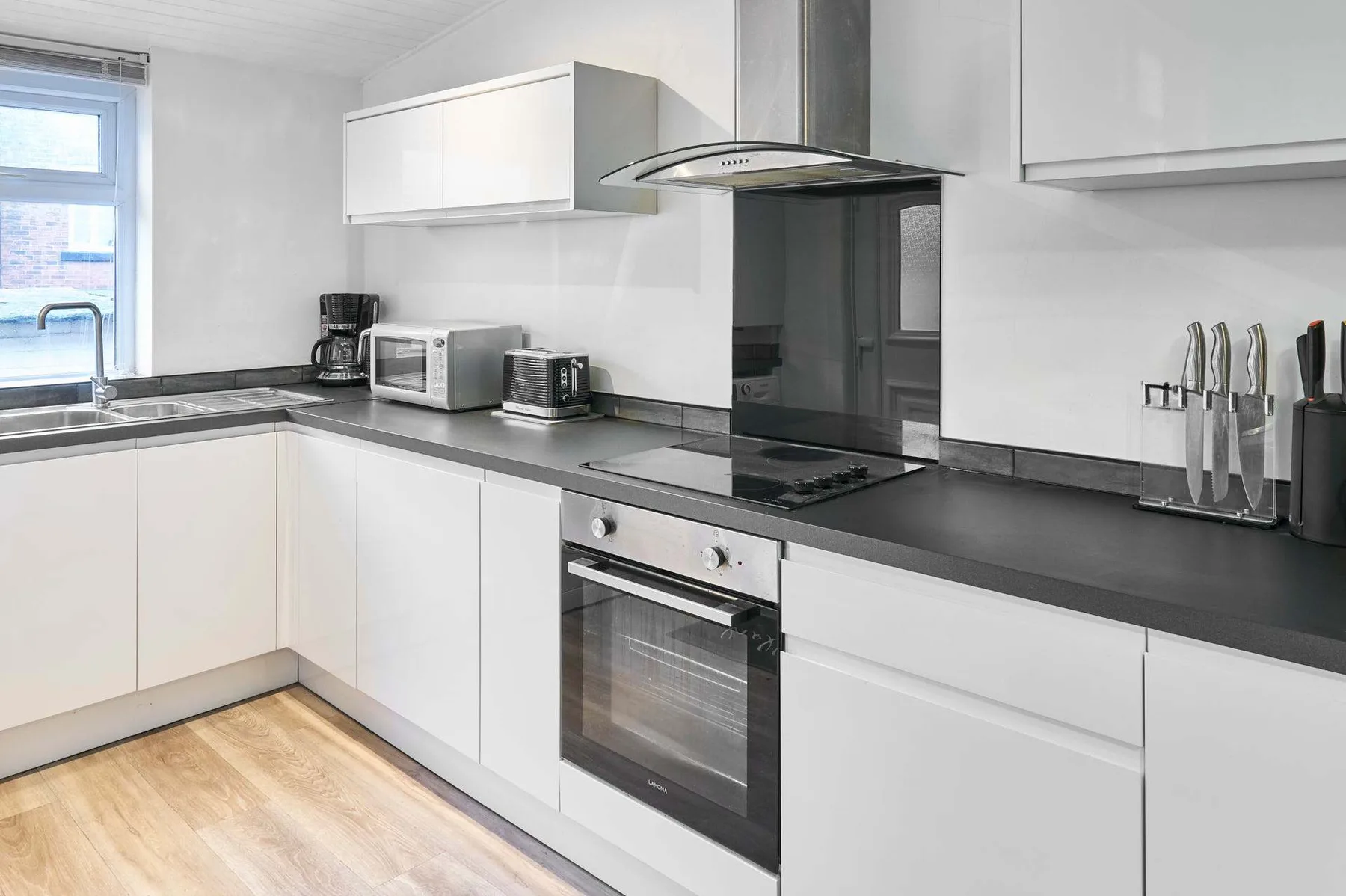 Una cocina moderna y luminosa con gabinetes blancos y encimeras oscuras.