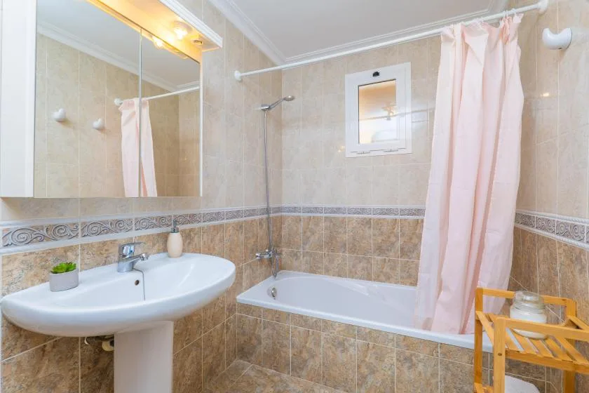 A bathroom with a bathtub, sink, and pink shower curtain.