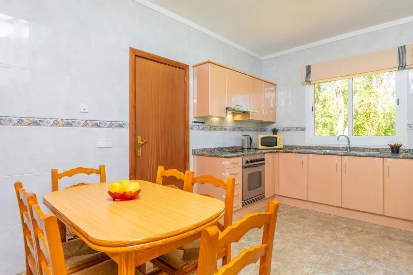 A kitchen and dining area with a wooden table beside the cabinets.