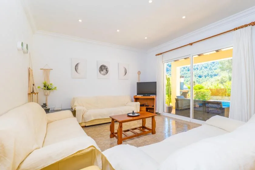 A bright living room with seating, a coffee table, and glass doors opening to a patio.