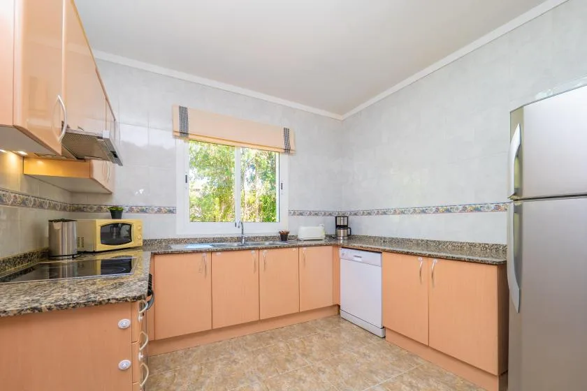 A kitchen with peach-colored cabinets, a countertop, and a window.