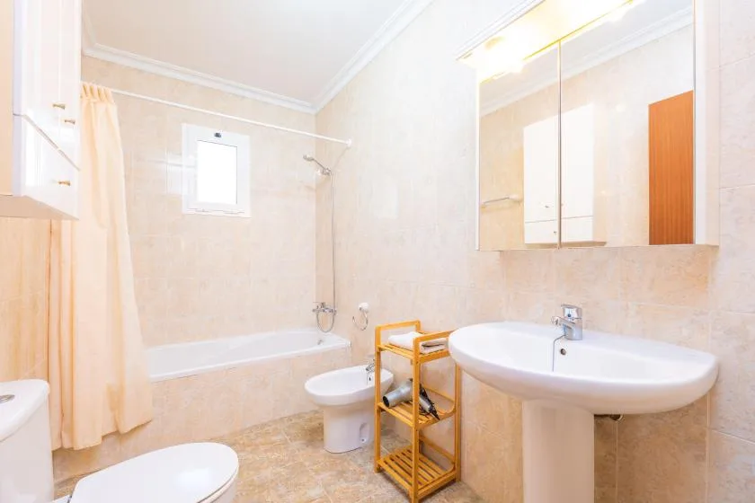 A tiled bathroom with a bathtub, toilet, and sink.