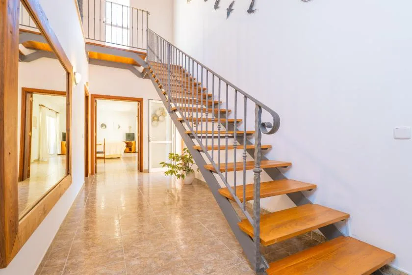 A staircase with wooden steps rises through a bright interior hallway.