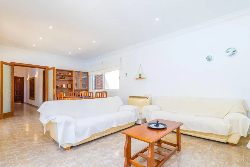 A bright living room with white seating and a wooden coffee table.