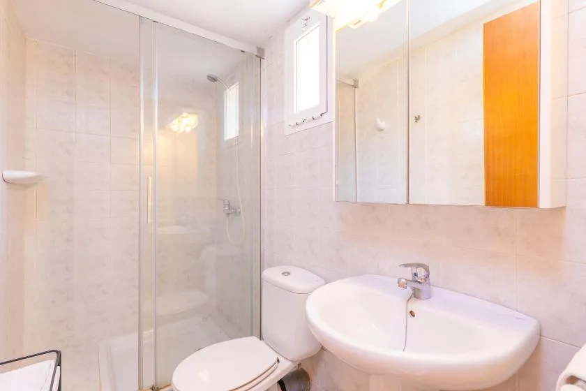 A bright bathroom with a glass shower and a wall-mounted sink.