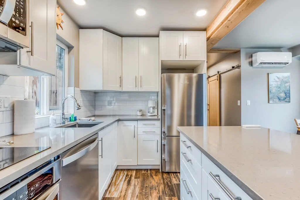 Una cocina luminosa con gabinetes blancos, electrodomésticos de acero inoxidable y una isla grande.