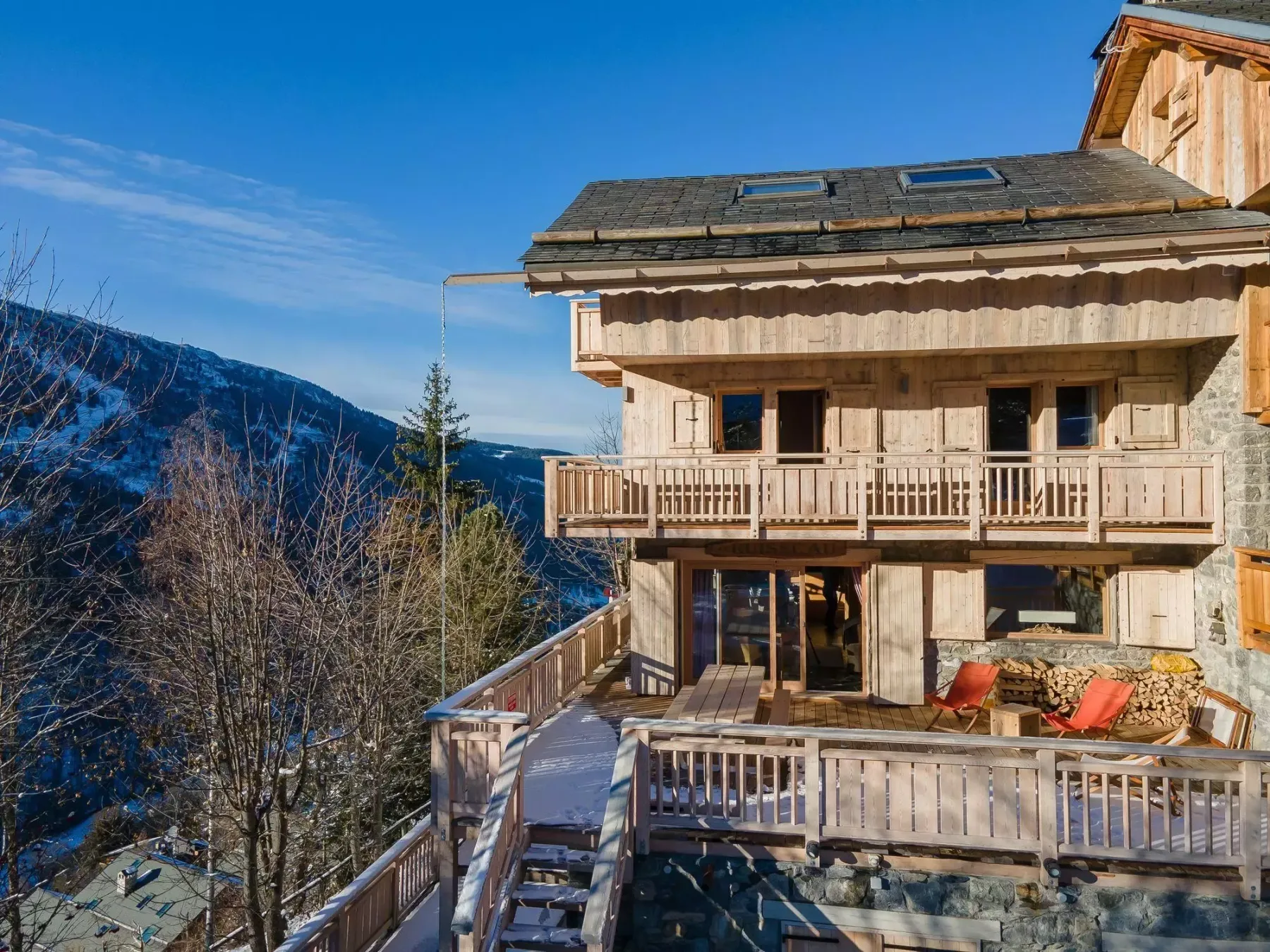 Un chalet de madera con una amplia terraza mira hacia un paisaje montañoso.