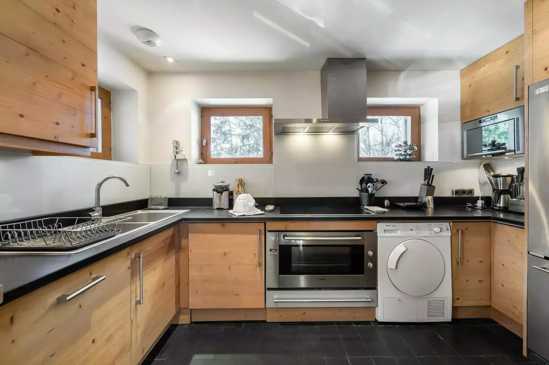Una cocina con gabinetes de madera, encimeras oscuras y electrodomésticos integrados.
