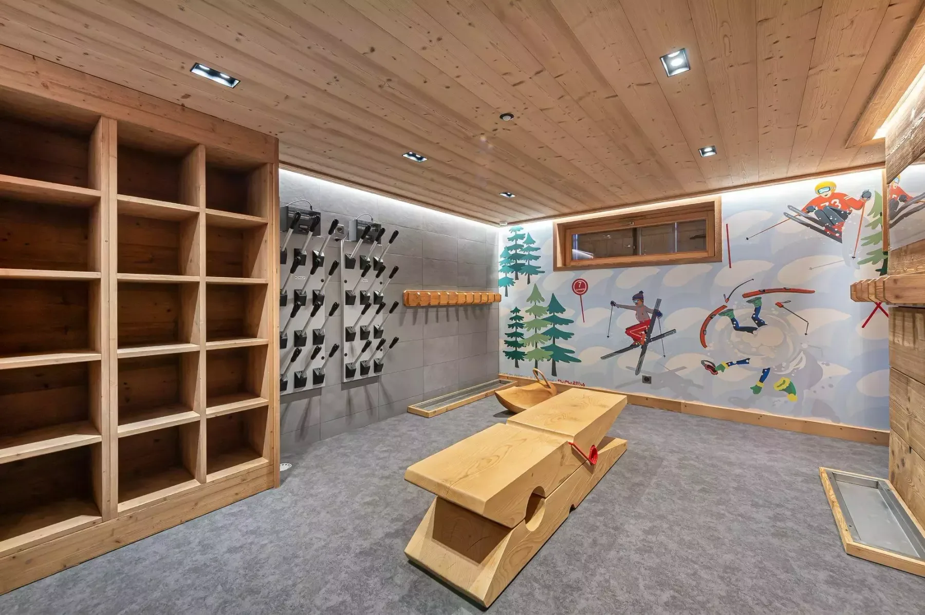 Una sala recreativa interior con estanterías de madera y una pared ilustrada y colorida.