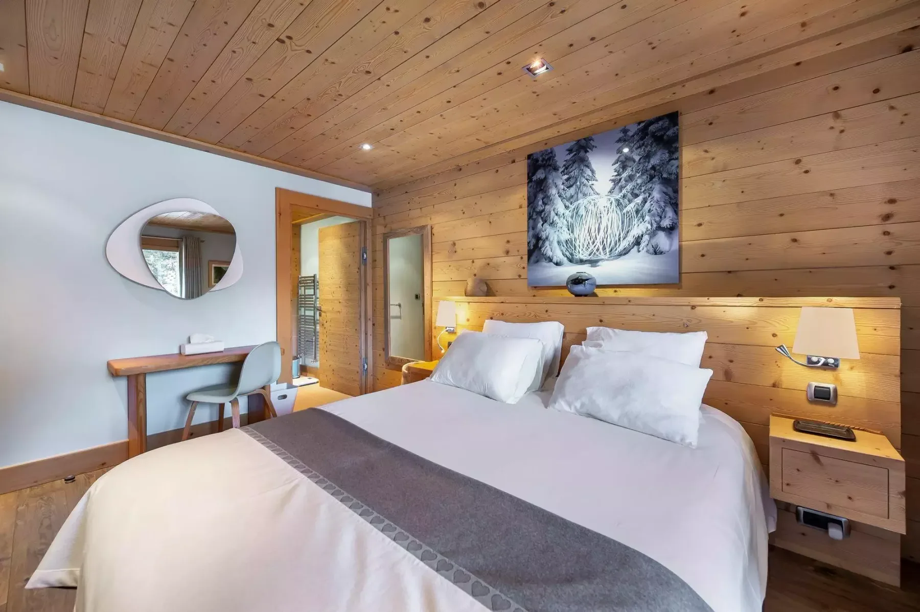 Un dormitorio con una cama, paredes revestidas de madera y un pequeño escritorio.