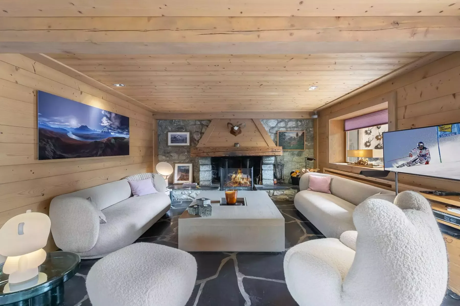 Sala de estar revestida de madera, con asientos alrededor de una chimenea central.