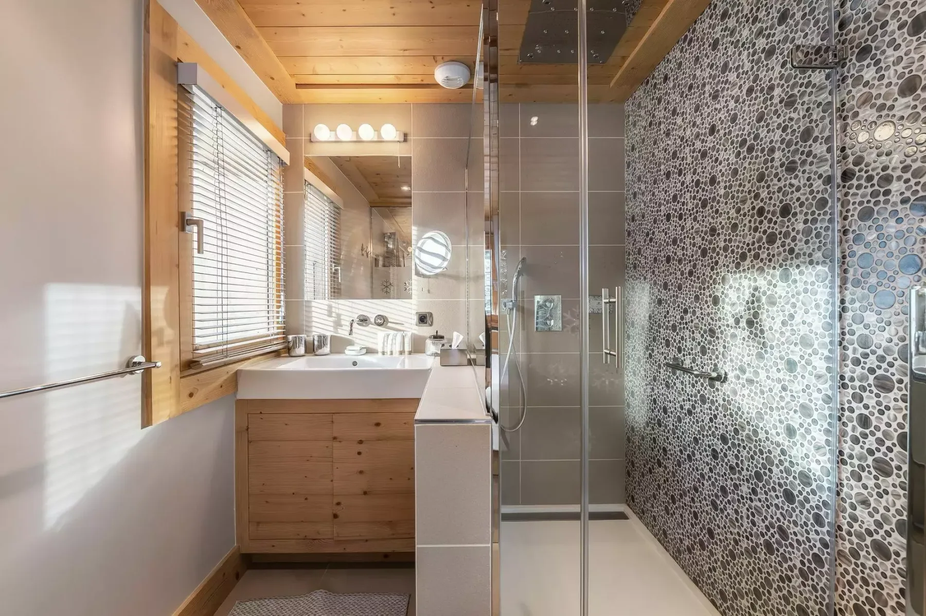 Un baño con tocador de madera, un espejo grande y una ducha de vidrio.