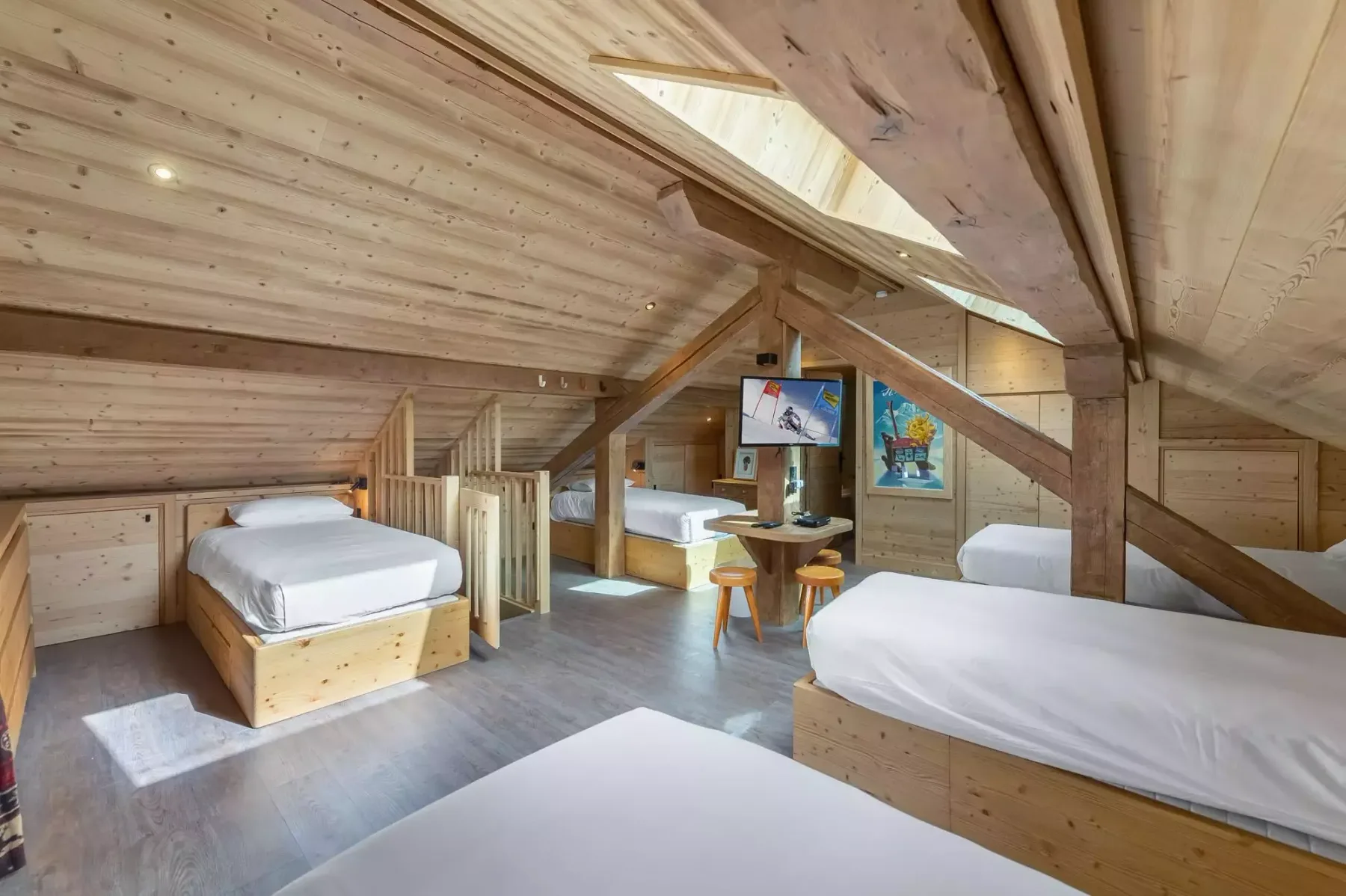Dormitorio abuhardillado con paneles de madera, varias camas y una claraboya.