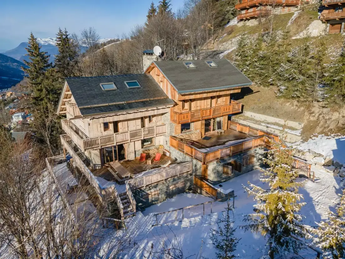 Un gran chalet en la ladera domina un paisaje montañoso nevado.