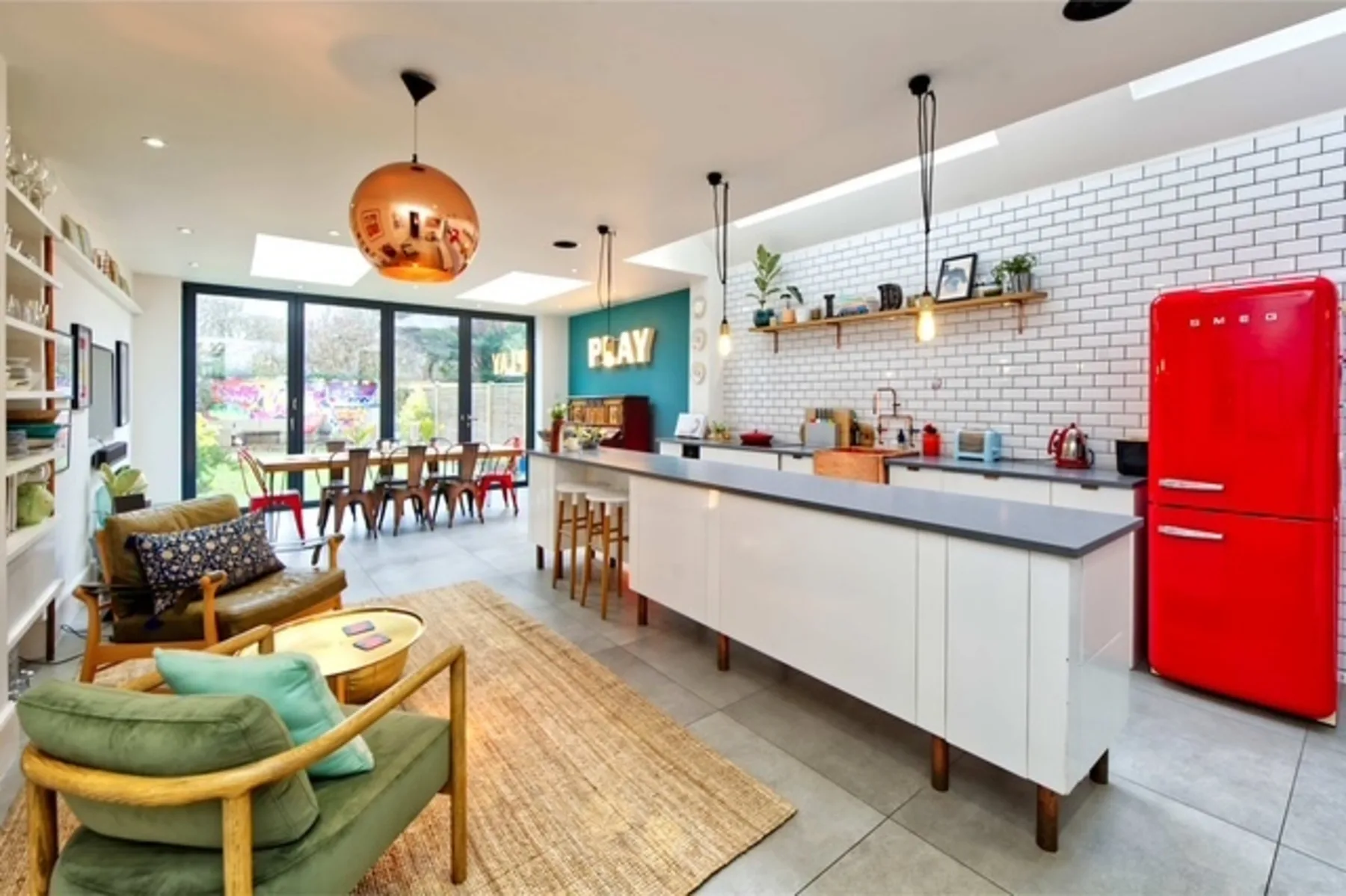 Cocina y comedor de concepto abierto, con asientos coloridos y una isla grande.