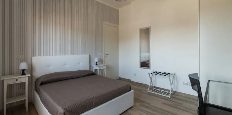 Un dormitorio con una cama doble, mesitas de noche y un perchero.