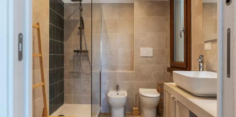 Un baño alicatado con ducha de vidrio, inodoro, bidé y lavabo.