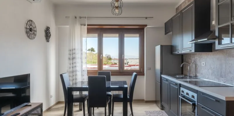 Una cocina con comedor y una mesa junto a las ventanas.