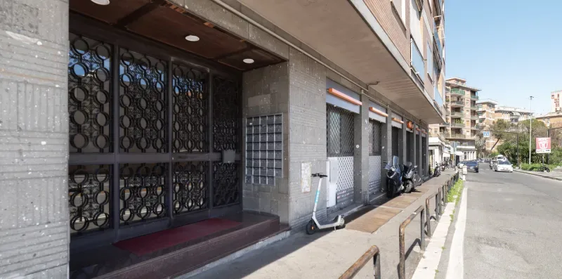 Vista de la calle con la entrada de un edificio, rejas decorativas y acera.