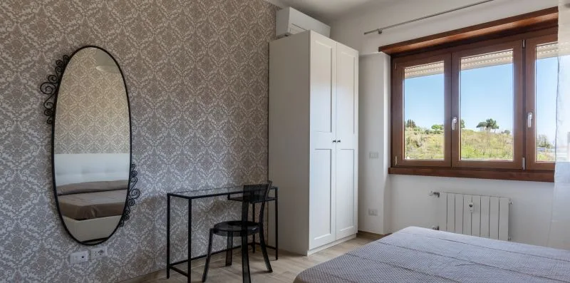 Dormitorio con cama, armario y ventanas grandes.