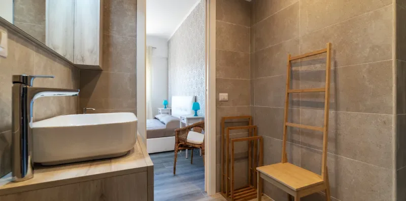 Un tocador de baño con lavabo da a un dormitorio con asientos.