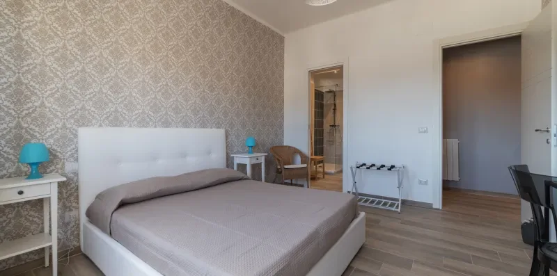 Un dormitorio con una cama grande, papel tapiz estampado y una pequeña zona de estar.