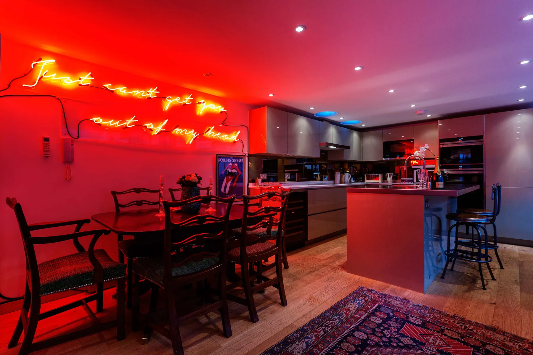 Un comedor y una cocina se iluminan con luz roja, con una mesa y asientos junto a la barra.