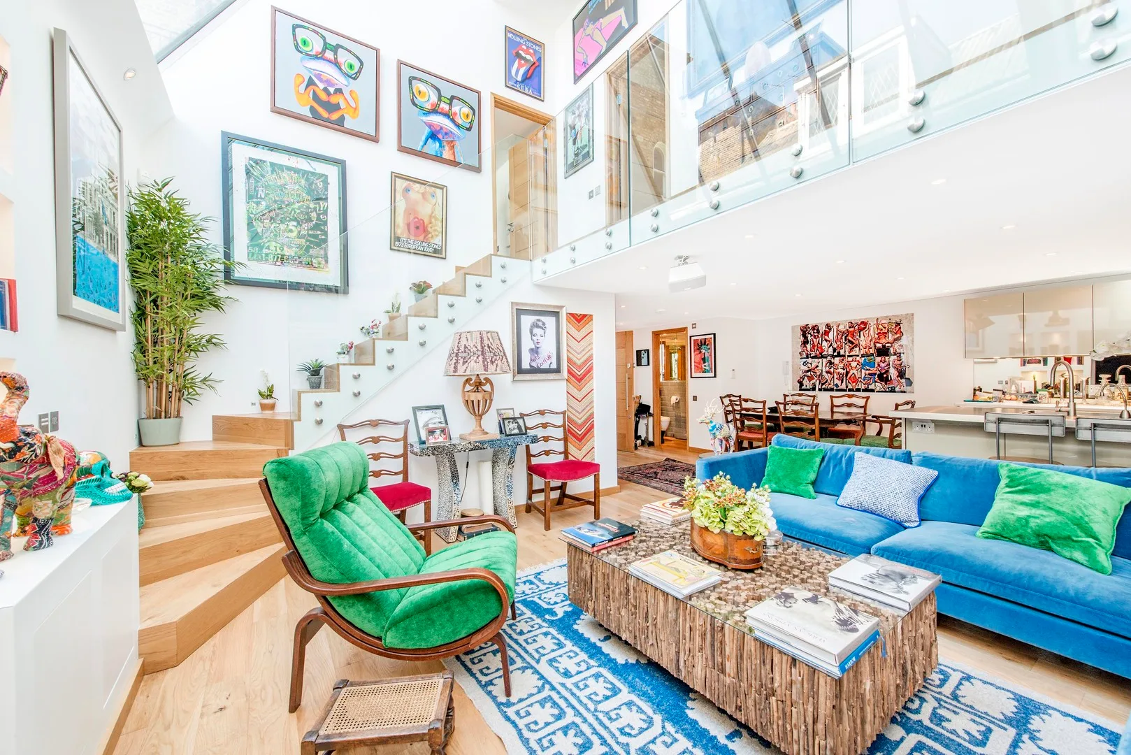 A bright open living room with colorful framed artwork and a blue seating area.