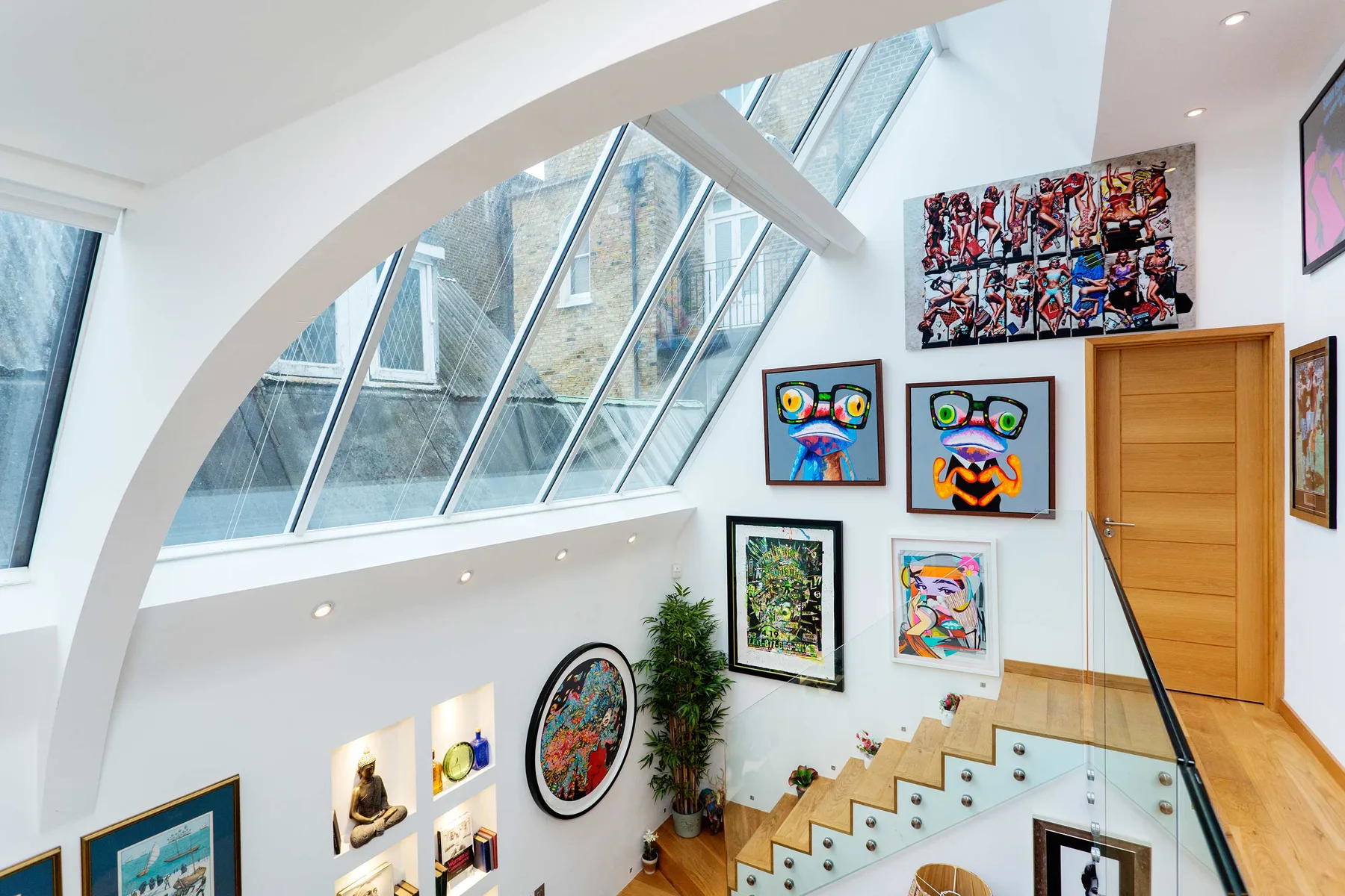 Una escalera luminosa decorada con arte presenta ventanas inclinadas y cuadros coloridos.