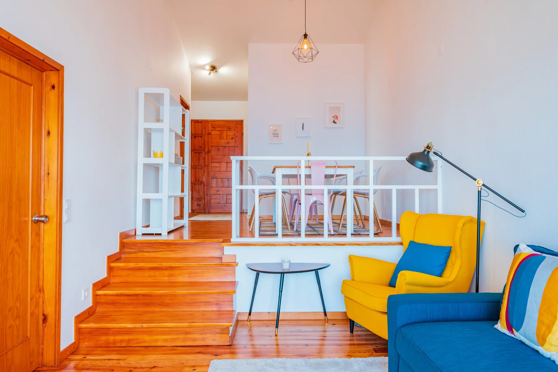 A bright living room with colorful seating and wooden steps.