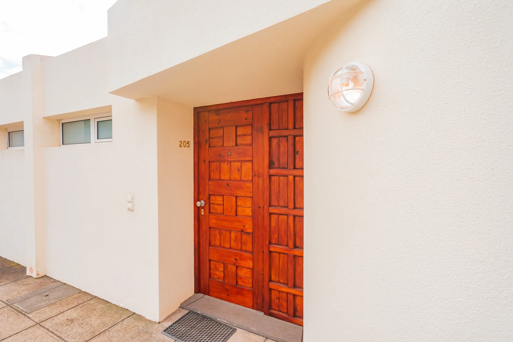 A wooden entrance door set into a white exterior wall.