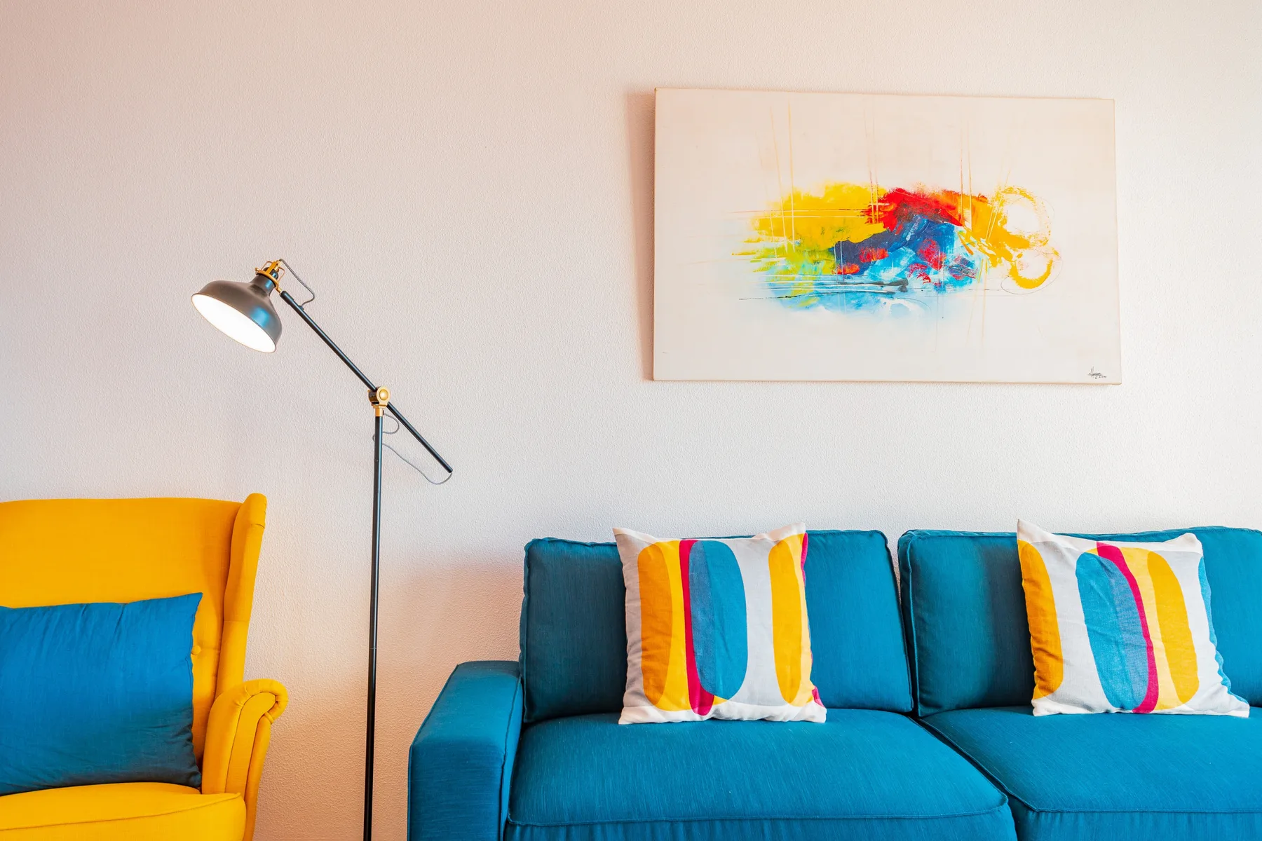 A colorful living room with blue seating and abstract artwork on the wall.